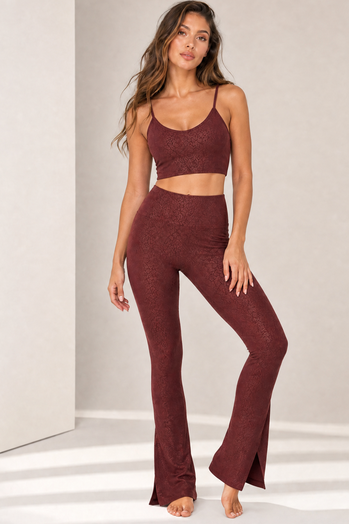 Model wearing the Paxton Bordeaux Jacquard activewear sports bra with matching Lisi Bordeaux Jacquard flare leggings. This coordinated workout set features a supportive scoop-neck sports bra, high-waisted flared leggings with front slit hems, and a subtle tonal jacquard pattern for yoga, Pilates, training, and everyday athleisure.