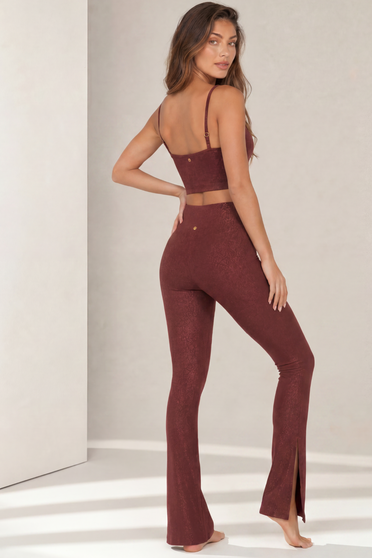 Three-quarter back view of the Paxton Bordeaux Jacquard activewear set featuring a longline sports bra with adjustable straps and high-waisted flare leggings with front slit hems. The figure-flattering silhouette and stretch performance fabric are designed for movement and all-day comfort.