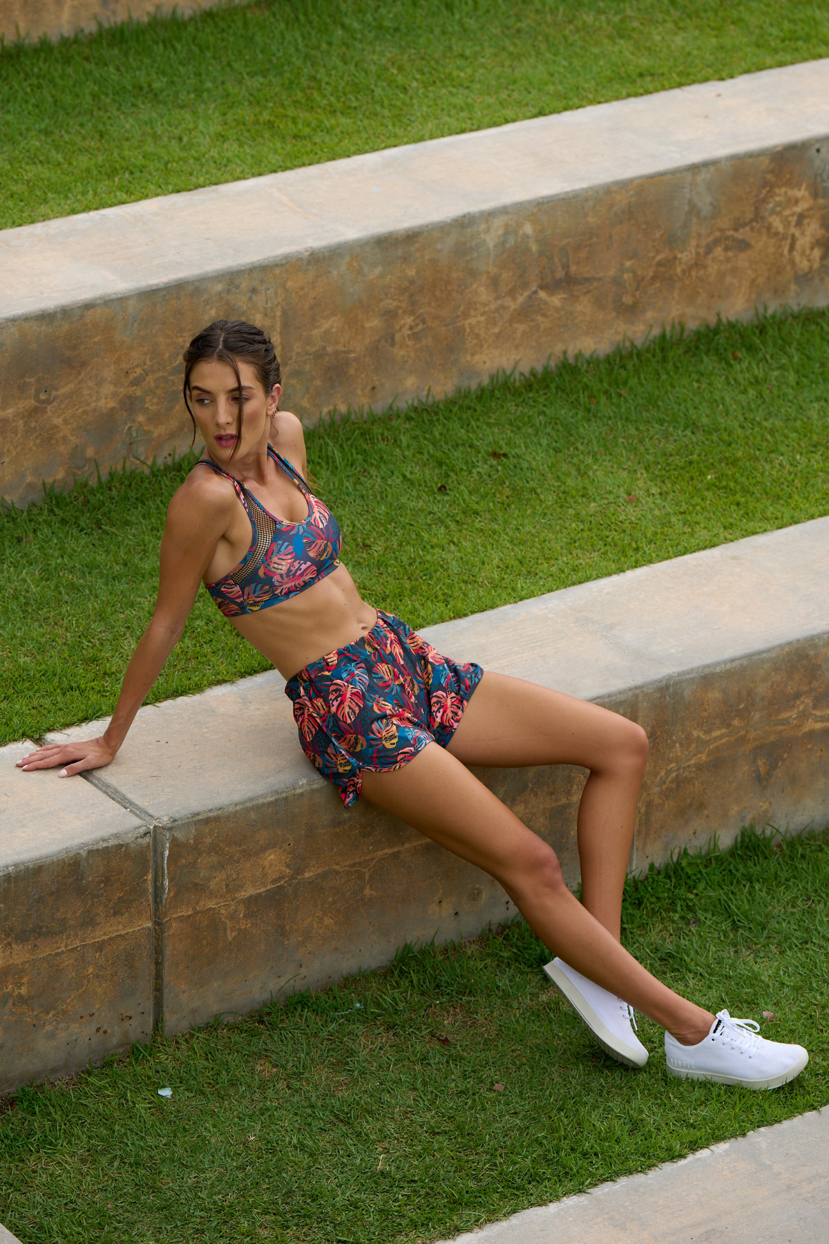Woman wearing a colorful sports bra and shorts set with a blurred natural background