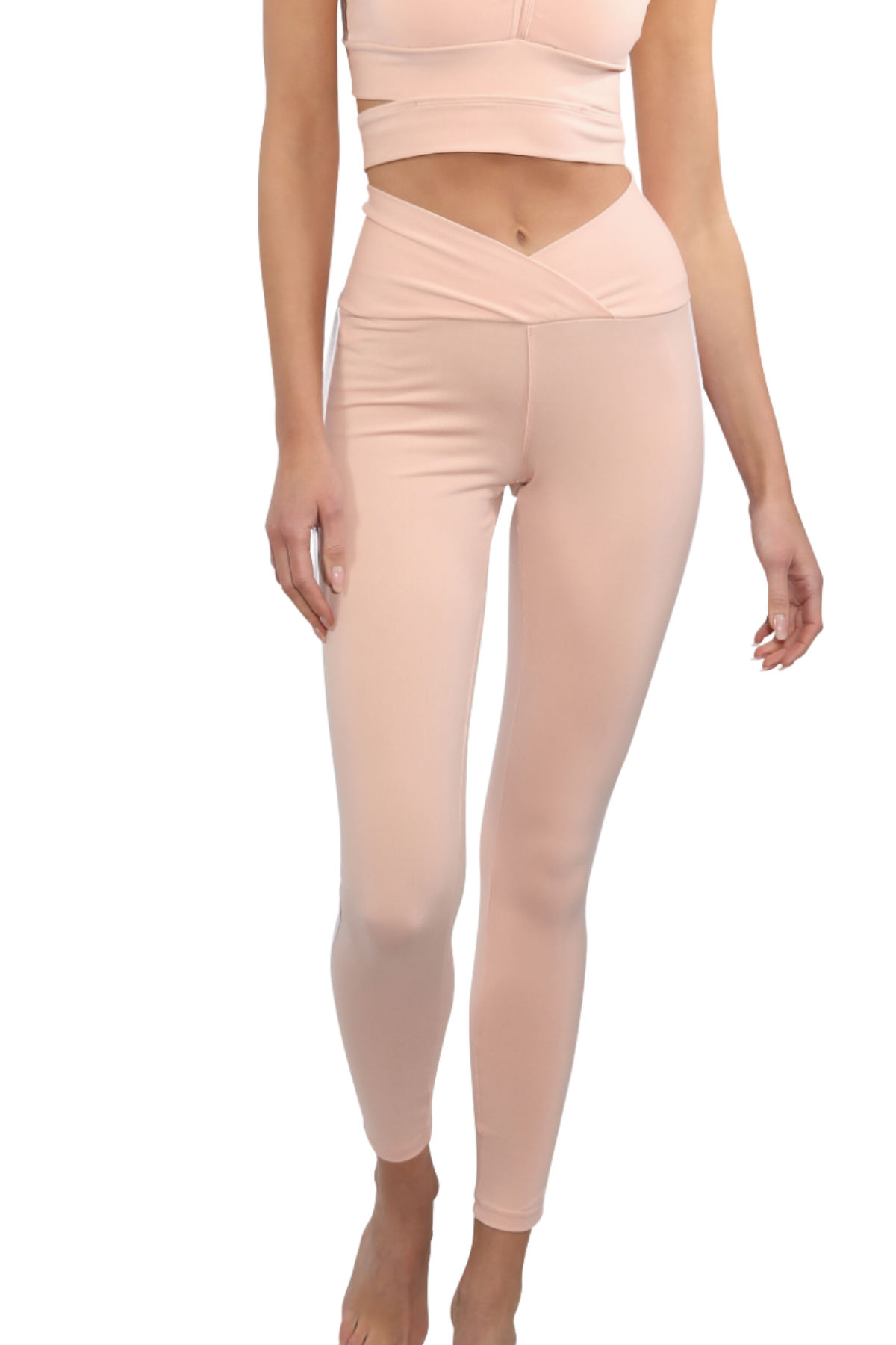 A model wearing high-waisted, form-fitting leggings in a pale peach-pink color, paired with a matching sports bra, shown against a plain white background.